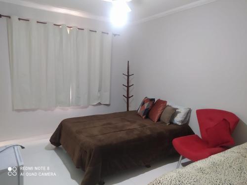 1 dormitorio con 1 cama y 1 silla roja en Suíte praia dos Anjos, en Arraial do Cabo