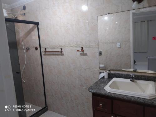 ein Badezimmer mit Waschbecken und Glasdusche in der Unterkunft Suíte praia dos Anjos in Arraial do Cabo