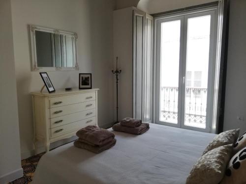 a bedroom with a bed and a dresser and a window at CASA PALACIO CABALLEROS 7 con Parking in Sanlúcar de Barrameda