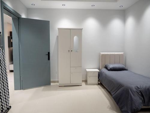 een slaapkamer met een bed en een witte kast bij Spacious apartments A in Riyad