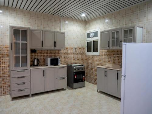 een grote keuken met witte kasten en een koelkast bij Spacious apartments A in Riyad
