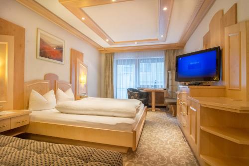 a hotel room with a bed and a flat screen tv at Alphotel Garni Salner in Ischgl