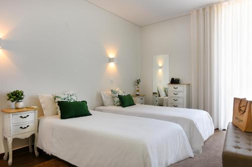 Quinta d'Anta- Hotel Rural في مايوركا: سريرين في غرفة بيضاء مع وسائد خضراء