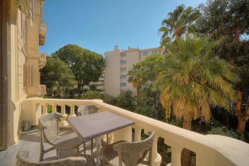 d'un balcon avec une table, des chaises et un palmier. dans l'établissement IMMOGROOM - T5 de standing - 130m - Terrace - Parking - AC, à Cannes