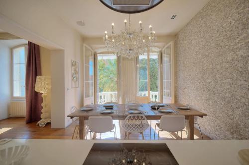 une salle à manger avec une table, des chaises et un lustre dans l'établissement IMMOGROOM - T5 de standing - 130m - Terrace - Parking - AC, à Cannes