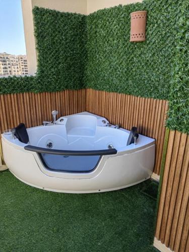 Cordoba suites Penthouse with private open air Jacuzzi في الغردقة: حوض استحمام أبيض أمام جدار أخضر