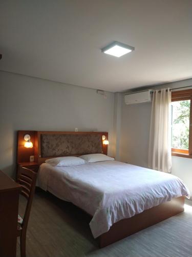 een slaapkamer met een groot bed en een raam bij Apartamento Tomasini in Gramado