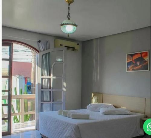 a bedroom with a large white bed and a window at Pousada Sol e Praia in Torres