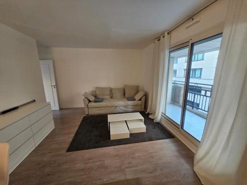 - un salon avec un canapé et une grande fenêtre dans l'établissement Appartement super, à Neuilly-sur-Seine