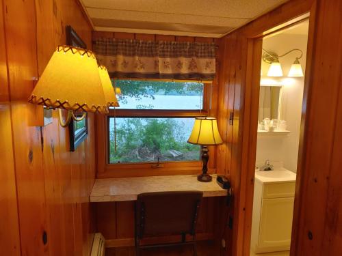 Zimmer mit einem Fenster und einem Schreibtisch mit einer Lampe in der Unterkunft Lakeshore Motel Ice Lake in Iron River
