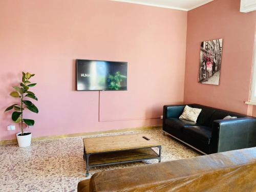 een woonkamer met een bank en een tv aan een roze muur bij Jane's Apartment Rental in Pisa