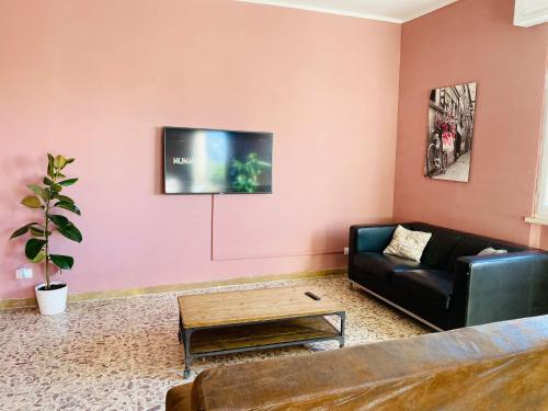 un soggiorno con divano e TV su una parete rosa di Jane's Apartment Rental a Pisa