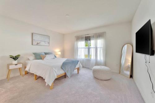 a white bedroom with a bed and a flat screen tv at Serene Sarasota Residence * By th Beach & Airport! in Sarasota