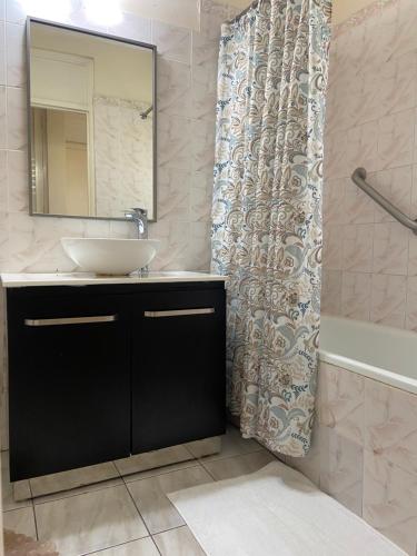 uma casa de banho com um lavatório, um espelho e uma banheira em Firefly at Sandcastle em Ocho Rios