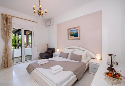 a white bedroom with a large bed and a chair at Villa Eleni 100m from the sea in Ropanianá