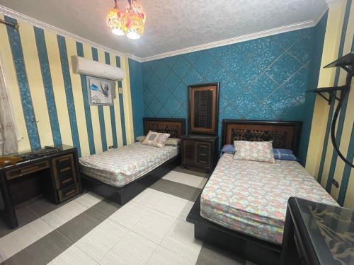 Duas camas num quarto com paredes azuis em شقة مفروشة مدينة نصر no Cairo
