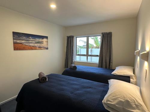 a bedroom with two beds and a window at Foreshore Mukies 2,0 in Ahipara
