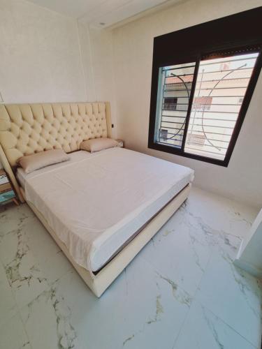 een slaapkamer met een bed, marmeren vloeren en een raam bij Eden jardin in Nador