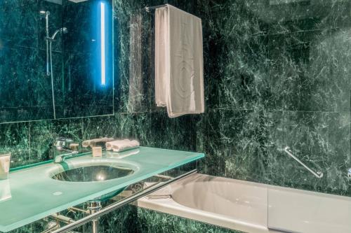 uma casa de banho com um lavatório e uma banheira em AC Hotel Valencia by Marriott em Valência