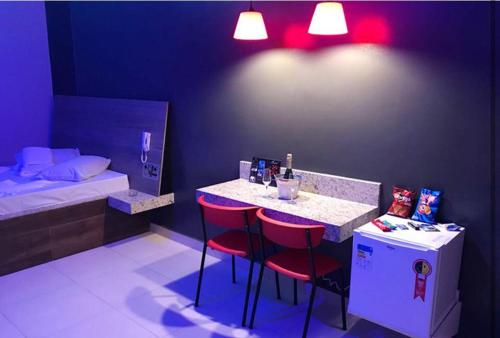 una habitación con un bar con sillas rojas y una cama en Motel Queen (Antigo Ícarus), en Lagoa Santa