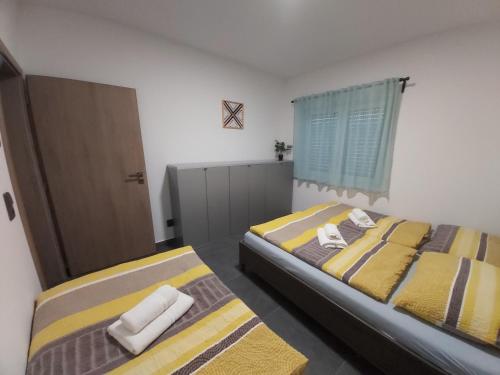 two beds in a bedroom with yellow and gray stripes at APARTMÁNY POD SJEZDOVKOU in Abertamy