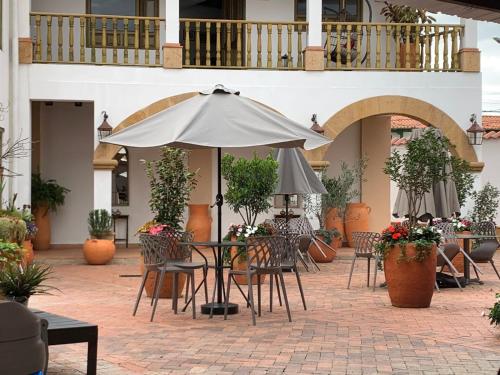 un patio al aire libre con mesas, sillas y una sombrilla en Santa Lucía Casa Hotel, en Villa de Leyva