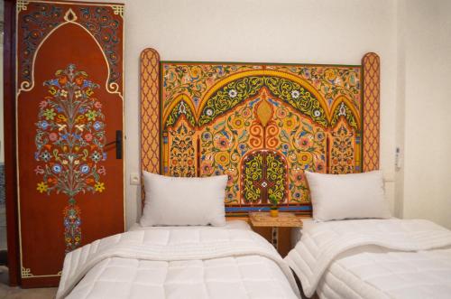 Zimmer mit 2 Betten und einer großen Wandkunst in der Unterkunft Dar Al Mardi Fes in Fès