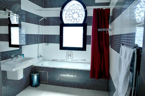 baño con bañera, lavabo y ventana en ABADA hôtel Mostagaem, en Mostaganem