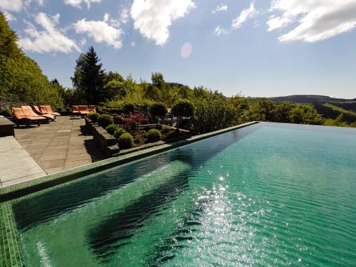 a swimming pool with blue water in a yard at Waldhaus Ohlenbach in Schmallenberg