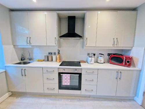 a kitchen with white cabinets and a red microwave at Central Reading Modern flat - Walk to station and high street in Reading