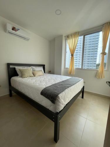 a bedroom with a large bed in front of two windows at Playa el Mansito Apartamento Ocean Sun in Punta Blanca