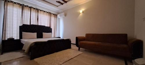 een slaapkamer met een bed, een bank en een raam bij Islamabad Layover Guest House Free Airport Pick and Drop in Islamabad