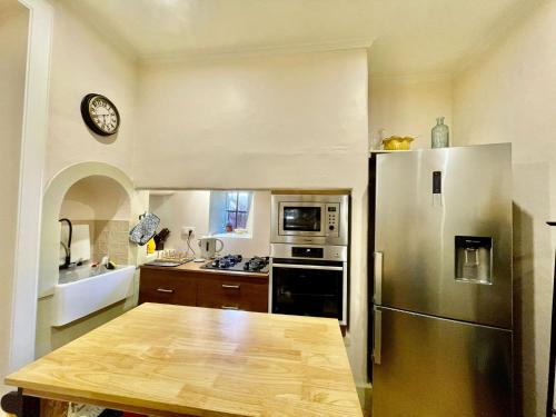 a kitchen with a stainless steel refrigerator and a wooden table at Quartos privados - Quinta da Paz in Santa Cruz