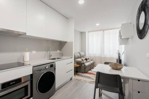 a white kitchen with a sink and a table at Great Location Very Central Boavista in Porto