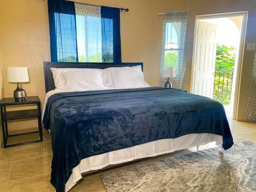 um quarto com uma cama grande e um edredão azul em Tamra’s Getaway em Montego Bay