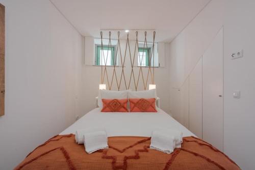 biała sypialnia z dużym łóżkiem z pomarańczowymi i białymi poduszkami w obiekcie Mint Flat in Foz by the Douro w Porto