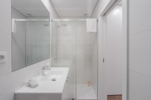 biała łazienka z prysznicem i umywalką w obiekcie Mint Flat in Foz by the Douro w Porto