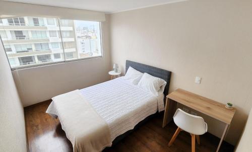 1 dormitorio con cama, escritorio y ventana en Moderno y acogedor cerca al mar en Lima