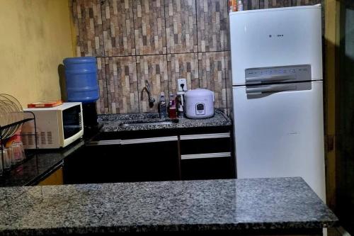 uma cozinha com um frigorífico branco e um lavatório em casa com, ar condicionado e suíte no major prates em Montes Claros