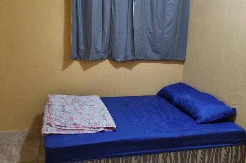 a small bed with a blue sheet and a window at casa com, ar condicionado e suíte no major prates in Montes Claros