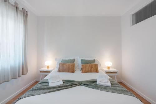 een slaapkamer met een groot wit bed met 2 lampen bij Central 2bed apt in Matosinhos in Matosinhos