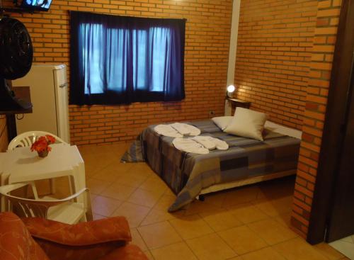 1 dormitorio con 1 cama en una pared de ladrillo en Pousada Parque da Cachoeira, en São Francisco de Paula