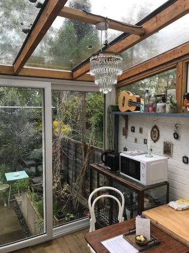 a kitchen with a table with a microwave and a window at Cosy hideaway with garden sauna in Cambridge in Cambridge