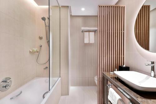 a bathroom with a tub and a sink and a shower at Courtyard by Marriott Dubai, Al Barsha in Dubai