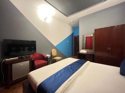 1 dormitorio con 1 cama, TV y silla en Bab Al Bahrain Hotel en Manama