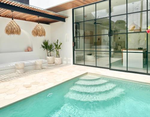 a swimming pool in a house with glass walls at The Suites by The Young Villas in Uluwatu