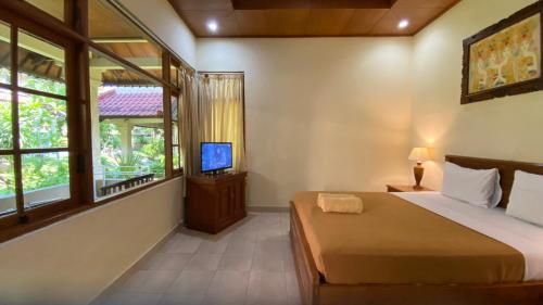 a bedroom with a bed and a television in it at Bali Sandy Resort in Kuta