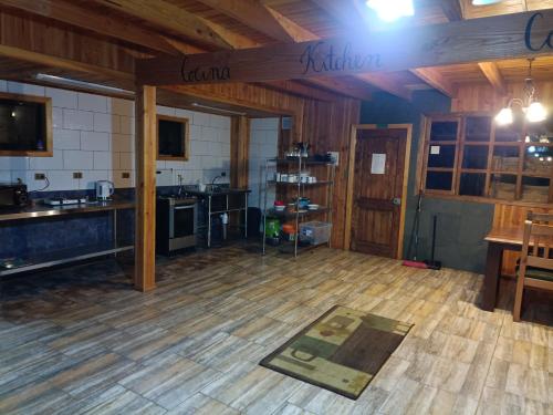 Habitación grande con cocina y suelo de madera. en Hostel Calafquen Coñaripe, en Coñaripe