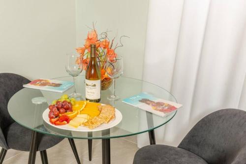 a glass table with a plate of fruit and a bottle of wine at Thatch Garden Apartment in Long Bay Village