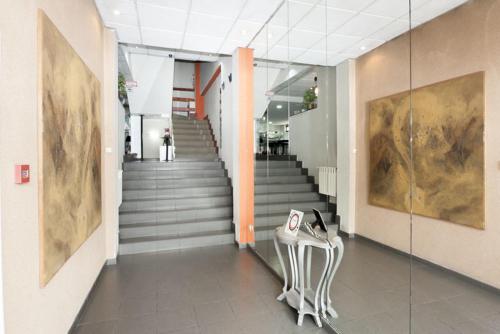 a hallway with a staircase with a chair and a table at Hotel Besaya in Torrelavega